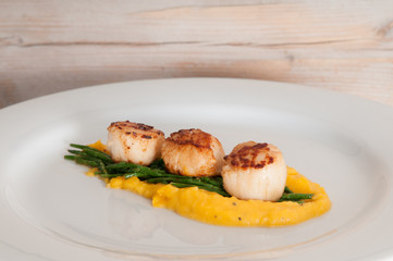 gourmet seafood dish of scallops and asparagus on a white plate