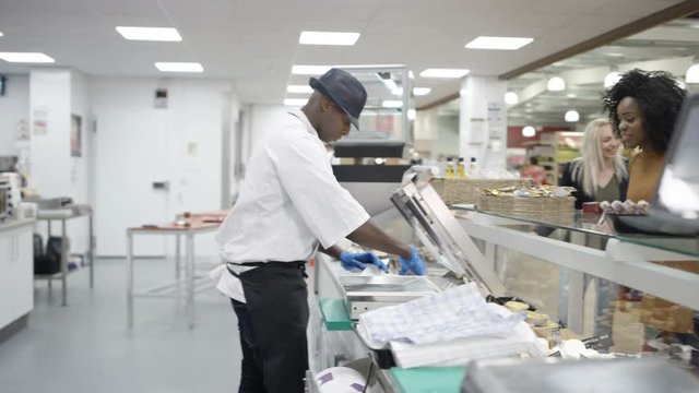  Happy worker on supermarket cheese counter serving customers & dancing