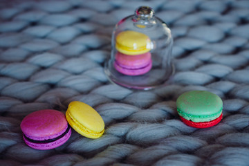 Green macaroon lies before glass cover on grey plaid