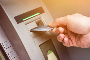 Hand of a man with a credit card, using an ATM. Man using an atm machine with his credit card.
