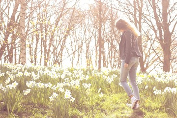 Happy young beautiful woman is walking along the spring blooming park. Portrait of a girl in the sunlight. Spring. Toned photo.