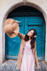 Woman holds her hat up posing before blue doors