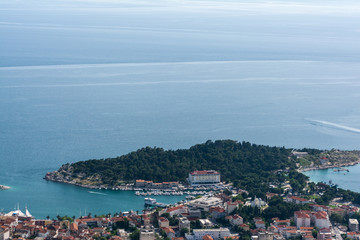 Fototapeta na wymiar Above view from the mountain on famous croatian resort Makarska. Sea, bay, ships, beach and red roofs of well-known resort town birds view.