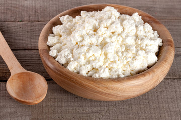 Cottage cheese in a wooden bowl on old wooden background