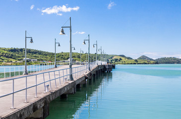 Long Concrete Pier Between Aqua Water and Blue Sky