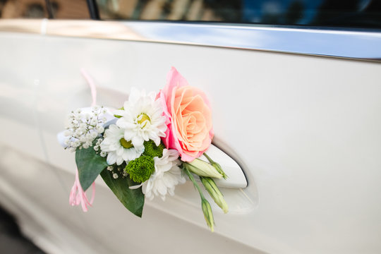 Daisies and rose put on handle of car door
