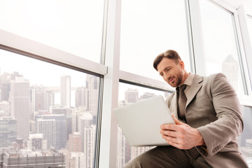 Fototapeta premium Low angle of serious businessman using laptop