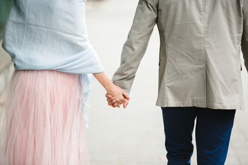 Look rom behind at man and woman in blue shawl holding their hands together