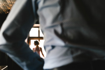 Fototapeta premium Look from behind man's back at stunning woman sitting before bright window