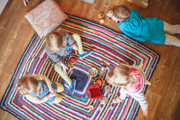 Top view of four little kids playing foods plates and tea time on the carpet on the floor in waldorf kindergarten