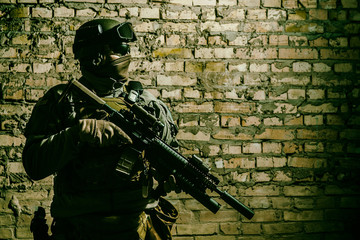 Special forces operator pointing weapon in the dark. Combat helmet, and bulletproof vest are on. Low key image, shadow soldier