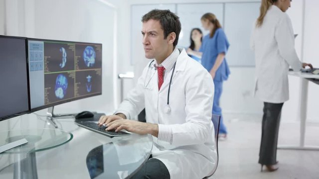  Portrait smiling doctor in modern clinic looking at patient scans on computer