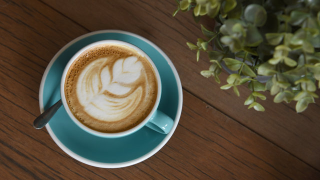 Nice texture of latte art coffee serve on wooden plate. Milk foam in heart shape leaf tree on top of latte art from professional barista artist