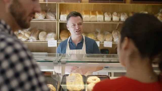  Couple in a bakery shop making contactless payment by cell phone