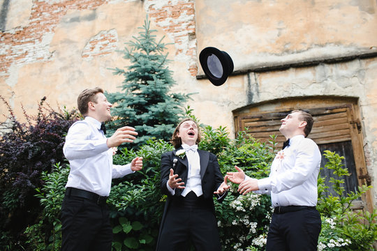 Groom with a stick throws topper to groomsmen