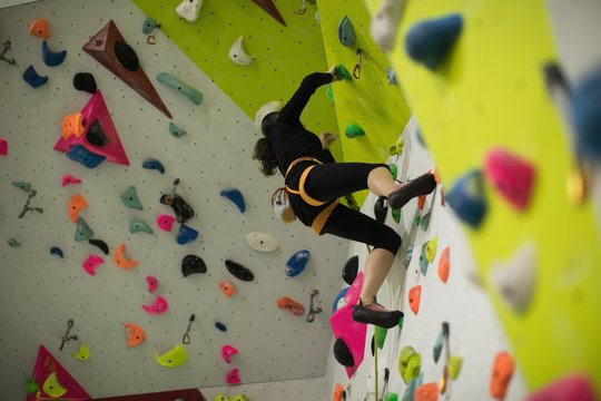 Woman practicing rock climbing on artificial climbing wall 