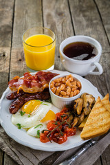 Obraz na płótnie Canvas Full english breakfast - eggs, bacon, beans, toast, coffee and juice