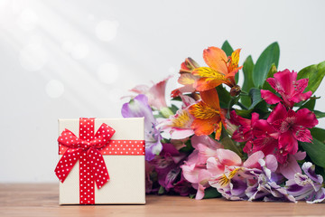 Gift box with spring flowers on wooden table, white background
