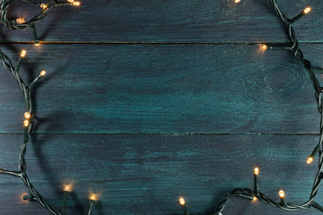 Fairy lights on a dark wooden texture, holiday background 