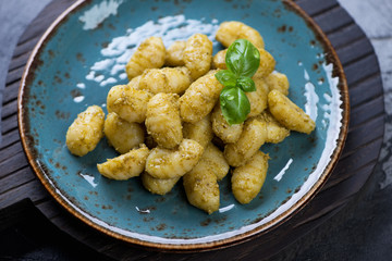 Closeup of potato gnocchi with basil pesto sauce on a turquoise plate, selective focus