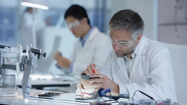  Electronics engineers working in the lab with manager overseeing
