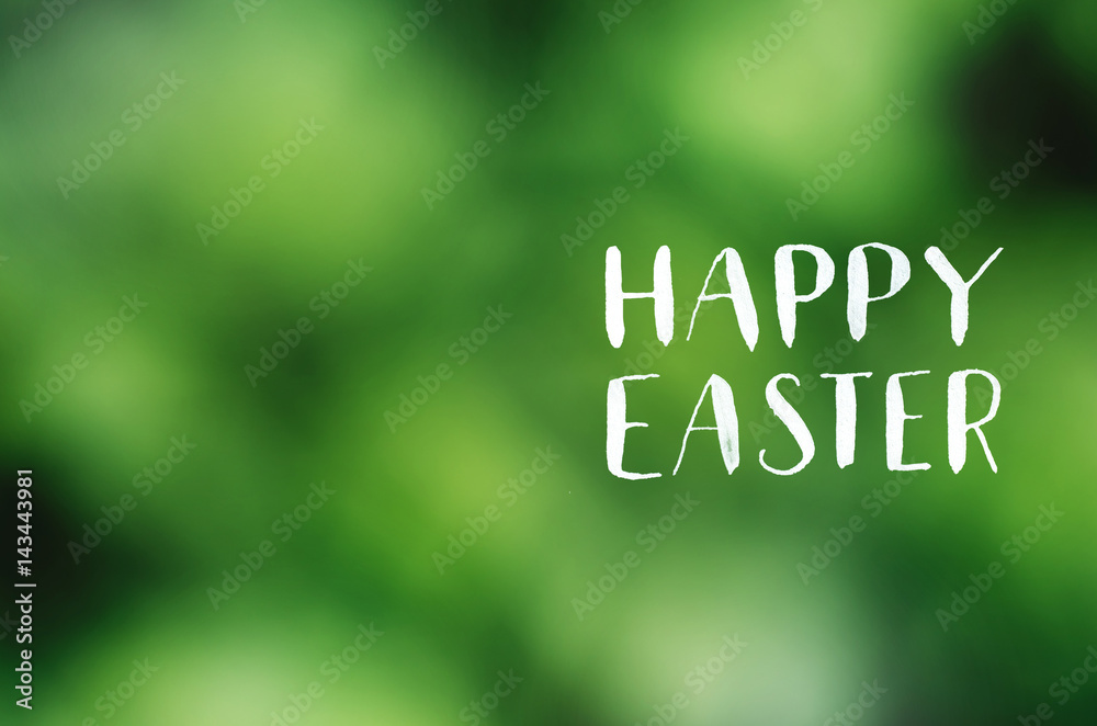 Wall mural happy easter lettering calligraphy on lens defocused green background. holiday postcard, poster, ban