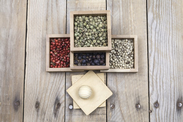 Several peppers, juniper and star anise on small wooden square bowls
