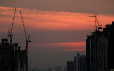 Stunning after grow of sunset sky over the working cranes of constructing site, Bangkok, Thailand 