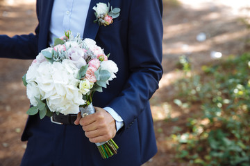 Wedding bouquet in groom hands, close up