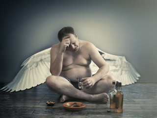 Male fallen angel with alcohol and a cigarette sitting on the floor. Habits, way of life, the...