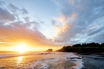 Obraz premium Beautiful balinese landscape. Ancient hinduism temple Tanah lot on the rock against sunset sky. Bali Island, Indonesia.