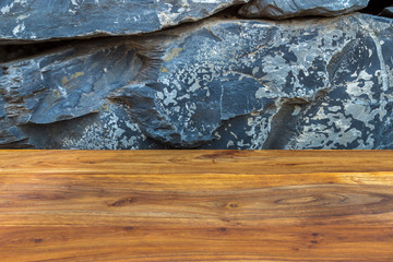 Treated reddish brown wood timber with exotic natural stonewall as background