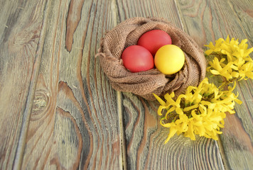 Easter color eggs are a holiday symbol. Eggs and flowers are on a wooden table.