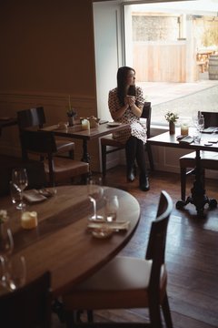 Woman having cup of coffee near window