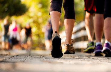 Fototapeta premium Close up of the legs of woman running on the wooden walkway in the park