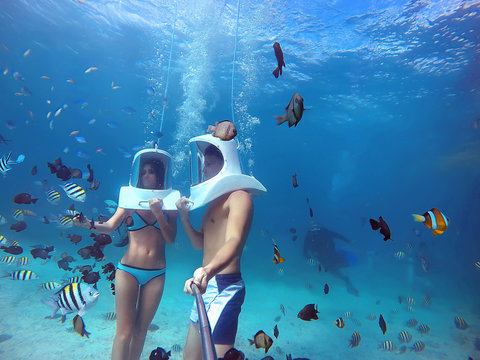Loving couple goes helmet diving together in tropical sea of Boracay during honeymoon and makes selfie on gopro