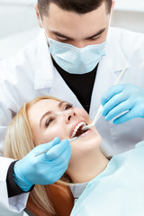 Working on her smile. Vertical closeup of a professional dentist examining teeth of a beautiful...