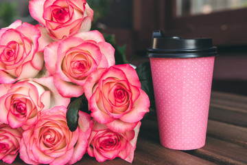 Take away coffee and  bouquet of pink roses on wooden background. Street coffee