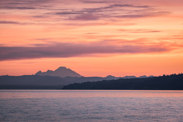 Dawn over Northwest Washington as a pink morning sky fills the frame above the volcanic Mount Baker and Puget Sound - obrazy, fototapety, plakaty