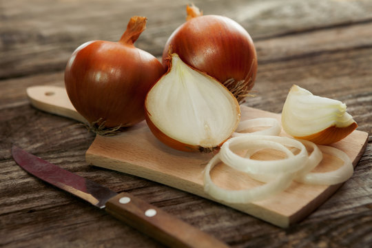 Fresh onion and onion cuts on chopping board