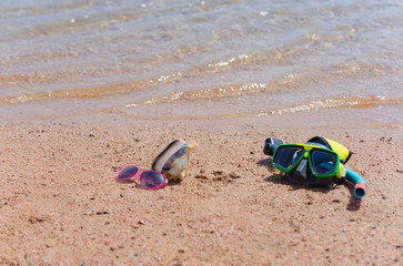 Fototapeta na wymiar Diving mask, sunglasses and marine shell on sandy beach