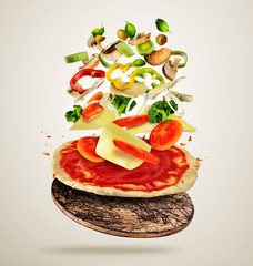 Ingrédients volants avec pâte à pizza, sur fond crémeux