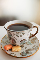 Beautiful cup of coffee with two caramel candies on the white table