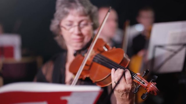  Symphony orchestra during a performance with focus on violinist. 