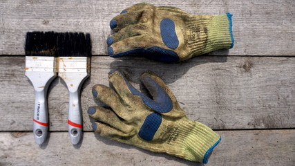 Old working gloves and brushes on the background of the wooden table