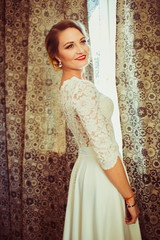 The beautiful bride stands near window