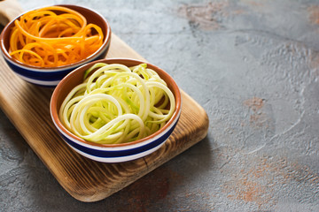 Spiralized butternut squash and courgette, zucchini on the grey stone background, selective focus, copy space for text