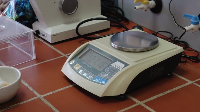 Small digital weights scales. Weigh the flask with a food product. Laboratory equipment. Confectionery factory. Quality check. Panorama.