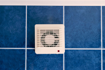 Air conditioner fan on blue tiled wall indoors