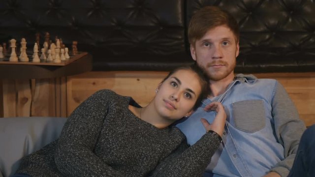 Couple in love watching TV and sitting on the pillows on floor